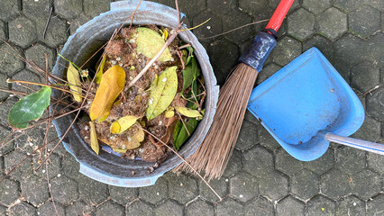 Obraz premium Seasonal cleaning of yellow falling leaves in the yard with garden tools. Filled Bucket, broom and shovels.