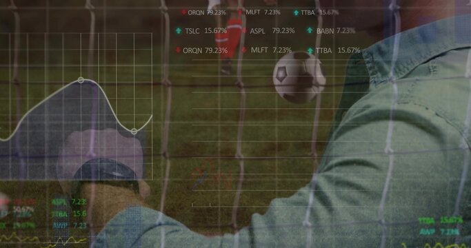 Man in green shirt analyzing tablet behind net, midair soccer ball, finance overlays, copy space