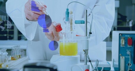 Scientist wearing lab coat holding test tube above yellow beaker on stir plate at bench, cables