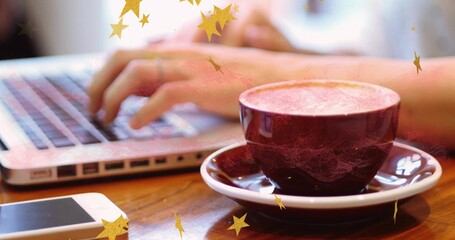 Resting maroon coffee cup on cafe table next to smartphone and typing on laptop, copy space