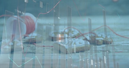 Showing red thread spool next to pastries drizzling white icing on wood table with financial charts