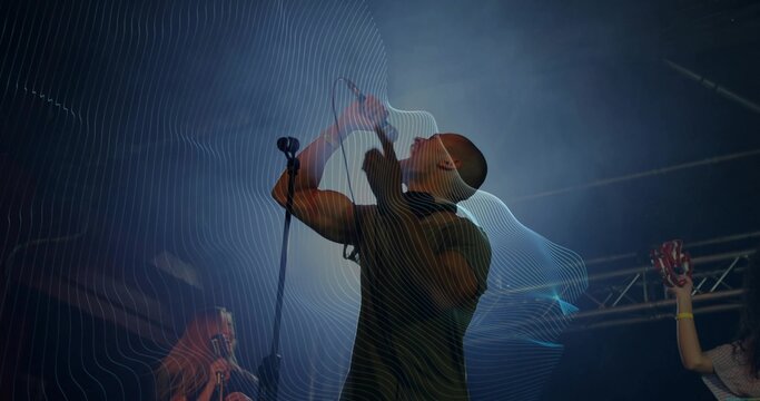 Singing lead vocalist gripping microphone on dark concert stage, with tambourine, spotlights, haze - Powered by Adobe