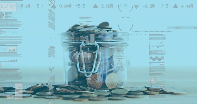 Transparent glass jar holding assorted coins on wooden surface in studio, with blue graphs
