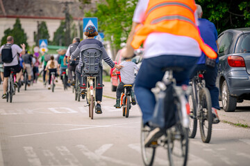 Children among group of cyclists on city road, street, asphalt
