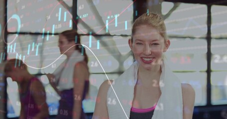Smiling fitness enthusiast posing in fitness studio with white towel and teenage girls near windows