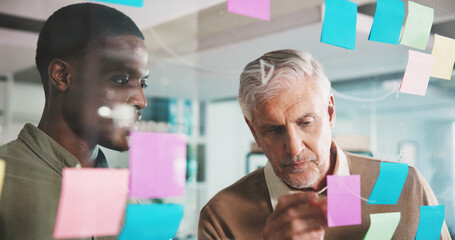 Mature man, glass wall and sticky note with team, coach and brainstorming for project at media company. Business people, board and employee with review, planning or collaboration at creative agency