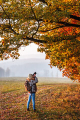 Woman with camera photographing colorful autumn leaves in nature. Hiking and photography hobby