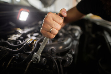A mechanic focuses on repairing an engine in a bright workshop, skillfully using a wrench to tighten bolts and ensure proper function.