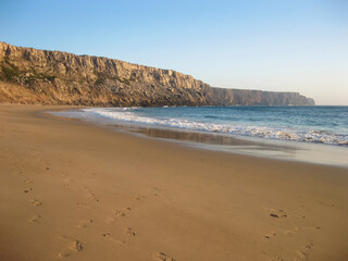 A beautiful sandy beach featuring a majestic cliff in the background