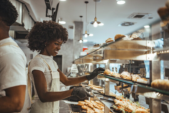 Confident Bakery Employee Arranging Delicious Fresh Pastries in a Display Case