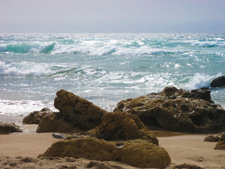 A beautiful beach featuring various rocks and waves crashing in