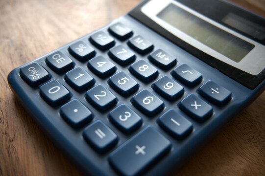 Close-up view of a blue calculator placed on a wooden desk.