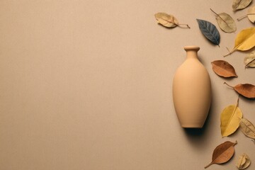 Beige vase surrounded by autumn leaves