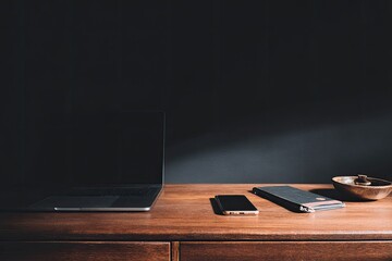 Modern workspace, dark backdrop, laptop, phone, notebook