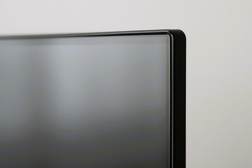 Close-up shot of a modern flat-screen display corner with minimal bezel design, highlighting sleek aesthetics and smooth reflective surface.