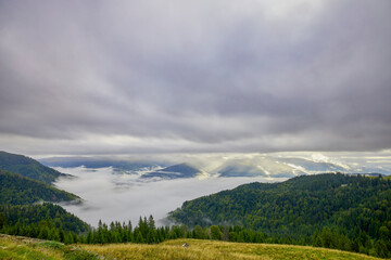 a beautiful mountain landscape in the Bucegi Mountains of Romania on a September day with clouds and fog.