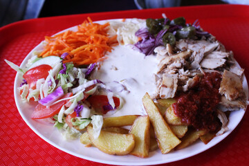 fast food. Shawarma on a plate, meat, potatoes, vegetables with white sauce on a plate