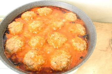 Meatballs in red tomato sauce cooking in a pan