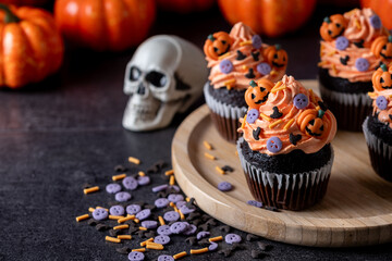 Halloween cupcakes with Halloween sprinkles on black surface . Copy space