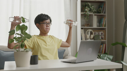 Asian man performing an overhead press with dumbbells at home.