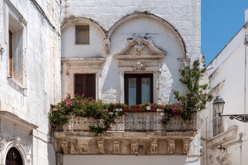 Fototapeta premium Architectural details showcasing a beautifully adorned balcony with flowers in a historic building located in a charming stone town under clear blue skies