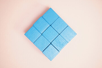 Blue wooden blocks carefully arranged in a symmetric pattern on a peach-colored surface, showcasing...