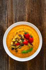 Garnished pumpkin cream soup on wooden table