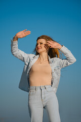 Woman enjoying a sunny day outdoors while playfully shielding her eyes from the sun