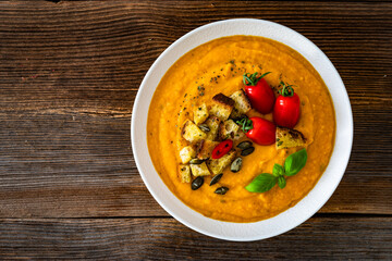 Garnished pumpkin cream soup on wooden table
