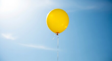 Obraz premium A Solitary Yellow Balloon Ascends into a Sun-Kissed Blue Sky with Lens Flare.