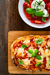 Pinsa Margherita and caprese burrata salad on wooden background
