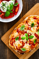 Pinsa Margherita and caprese burrata salad on wooden background