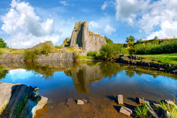 Fototapeta premium Panská skála, Czech Republic – Basalt formation reflected in water under blue sky. Impressive basalt landscape in Europe