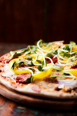 Pizza with chorizo ​​sausage, mozzarella cheese and yellow pepper. Rustic wooden background. Soft focus.	