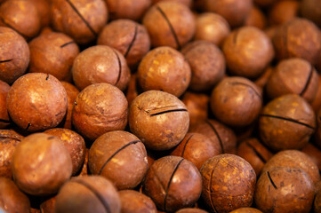 Macadamia nuts texture. Lots of fresh natural unpeeled raw macadamia nuts in full frame. Close-up of a pile of roasted macadamia nuts - top view