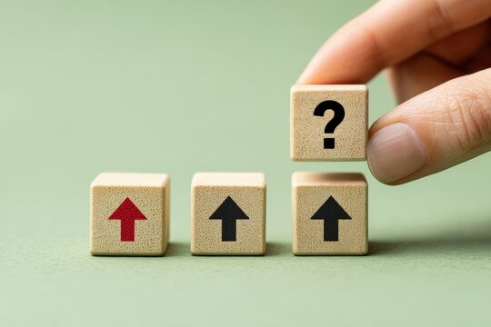A hand holds a wooden block with a question mark, while three other blocks display upward arrows