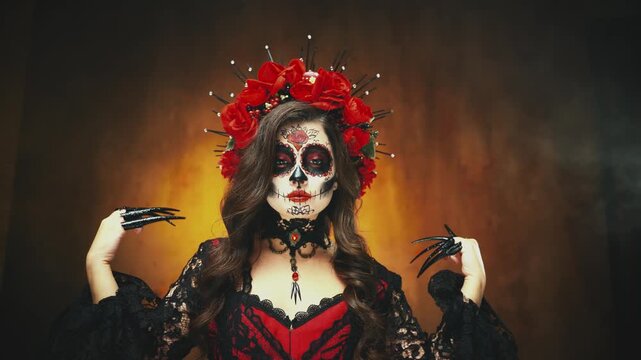 Closeup gothic fantasy woman with halloween make-up sugar skull sceleton body art beauty scary face red lips roses in wavy dark hair. sexy girl finger rings black claws longring posing with hands 4k