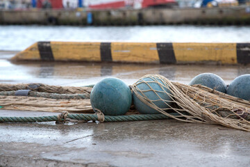 A collection of fishing nets and various buoys are scattered on the ground