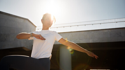 Woman practicing a dynamic pose outdoors under sunlight