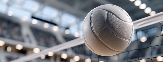Volleyball in motion above the net during a competitive match in a sports arena filled with excited fans
