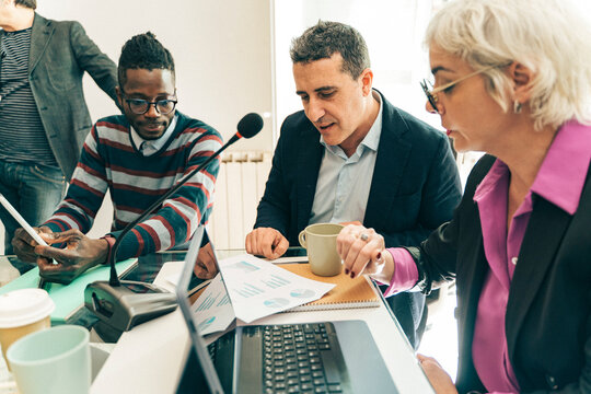 Diverse business team analyzing financial charts in a meeting. Colleagues collaborating on a project, concept of data analysis, teamwork and strategy.