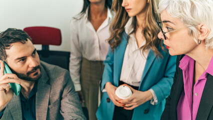 Diverse business team focused on an important phone call in a meeting. Colleagues collaborating on a problem, concept of negotiation, teamwork and urgent decision making in a modern office.