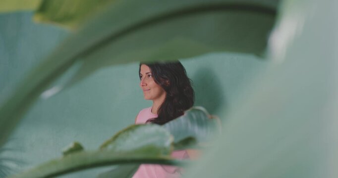 Confident smiling model posing for camera, seen through plant leaves