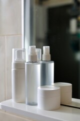 Care products, cosmetics and comb on the shelf in white bathroom. Cleanser, lotion, cream and comb near mirror. White bathroom. Women care products. Yellow comb. 