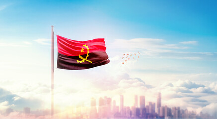 Angola flag wavering in beautiful clouds with building skyline. The flag with drone shot in beautiful sky. Angola national flag for independence day.