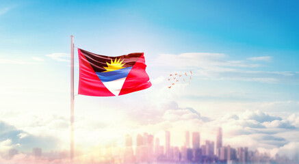 Antigua and Barbuda flag wavering in beautiful clouds with building skyline. The flag with drone shot in beautiful sky. Antigua and Barbuda national flag for independence day.