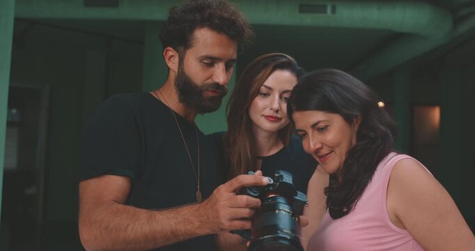 Photographer showing photos to two models in green screen studio, tilt shot