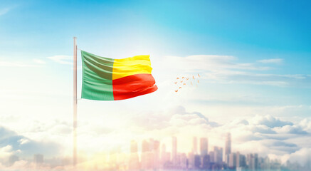 Benin flag wavering in beautiful clouds with building skyline. The flag with drone shot in...