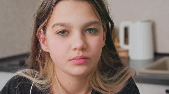 close up of young girl chewing and swallowing food in kitchen setting, utensils visible in background, natural light, candid moment, casual atmosphere, healthy eating, youth, lifestyle