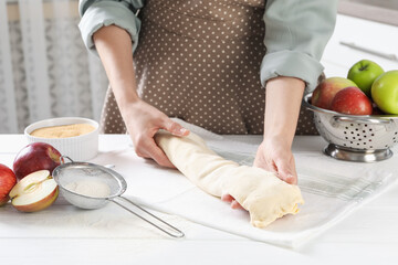 Woman making delicious apple strudel at white wooden table in kitchen, closeup